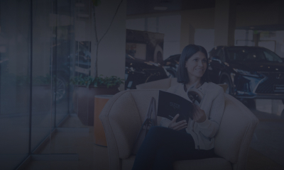 Woman sitting reading a Lexus brochure in a dealership
