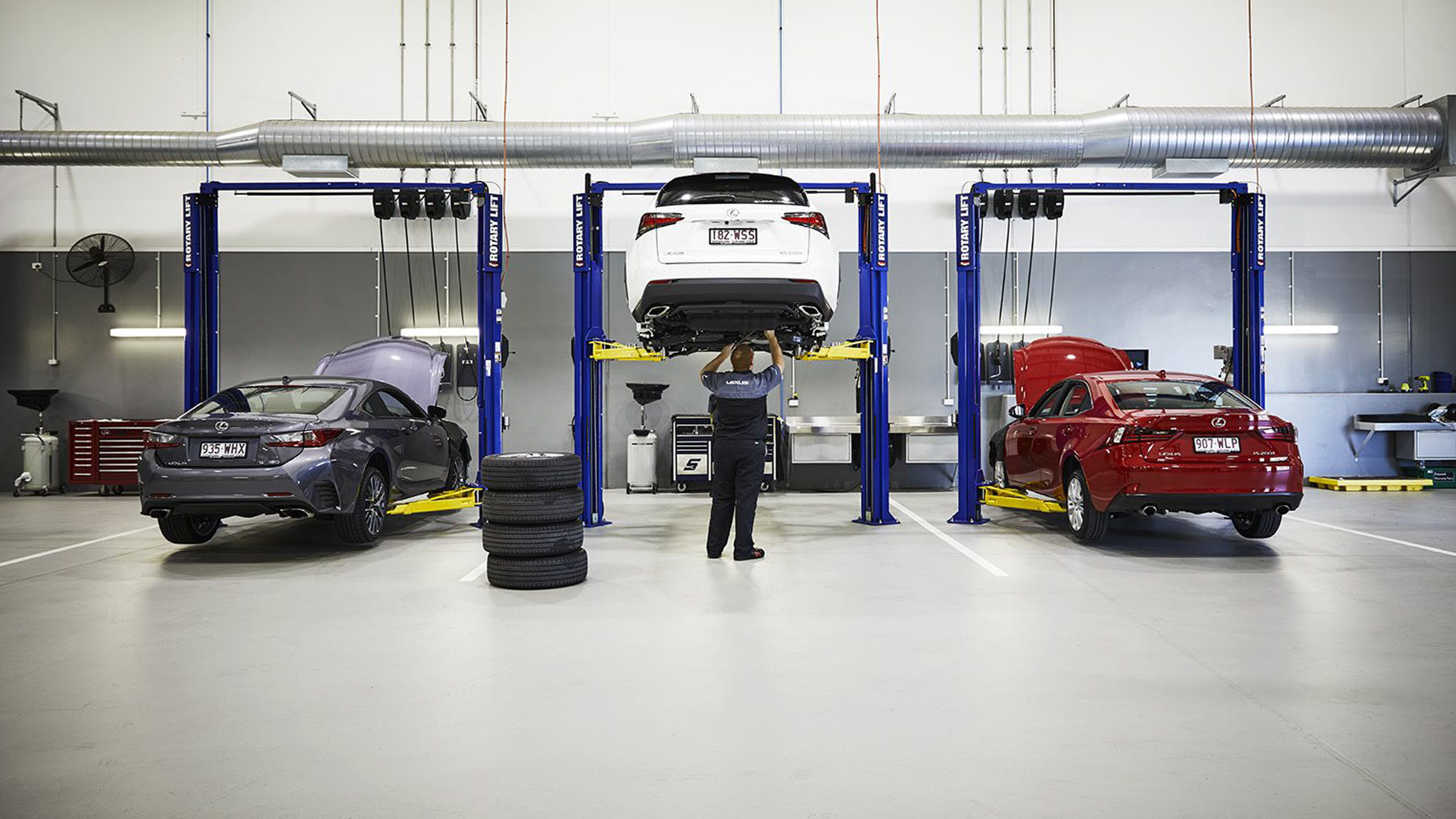 Lexus service center with three cars and a man standing in the middle