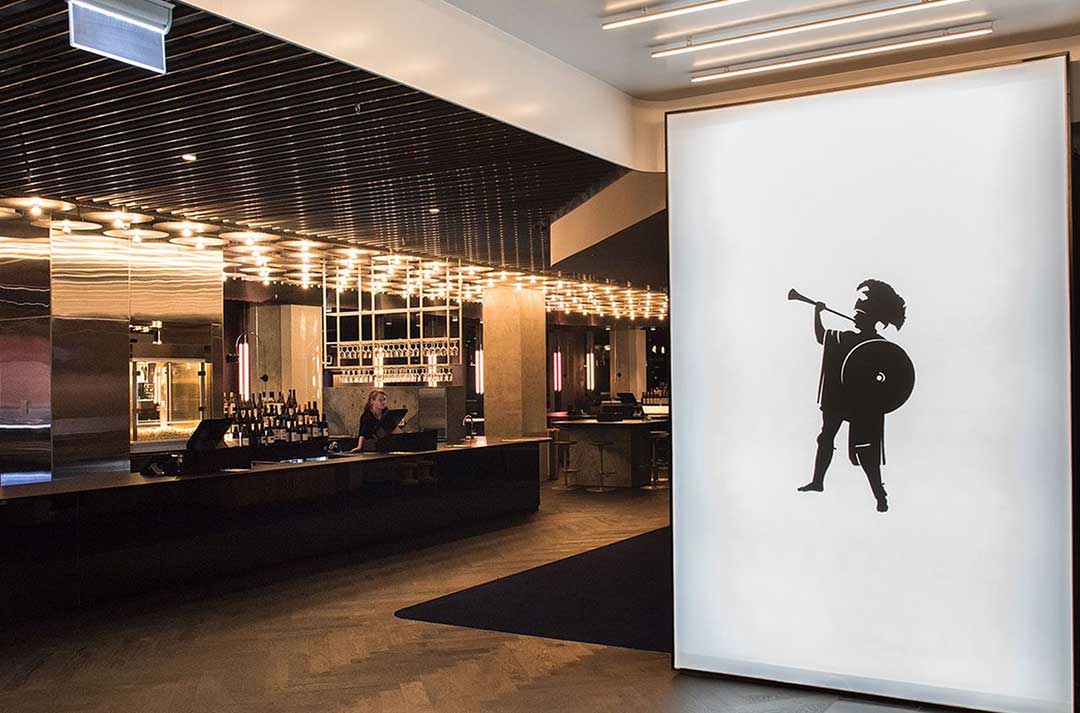 The foyer of a Palace Cinema featuring a bar and a large artwork display.