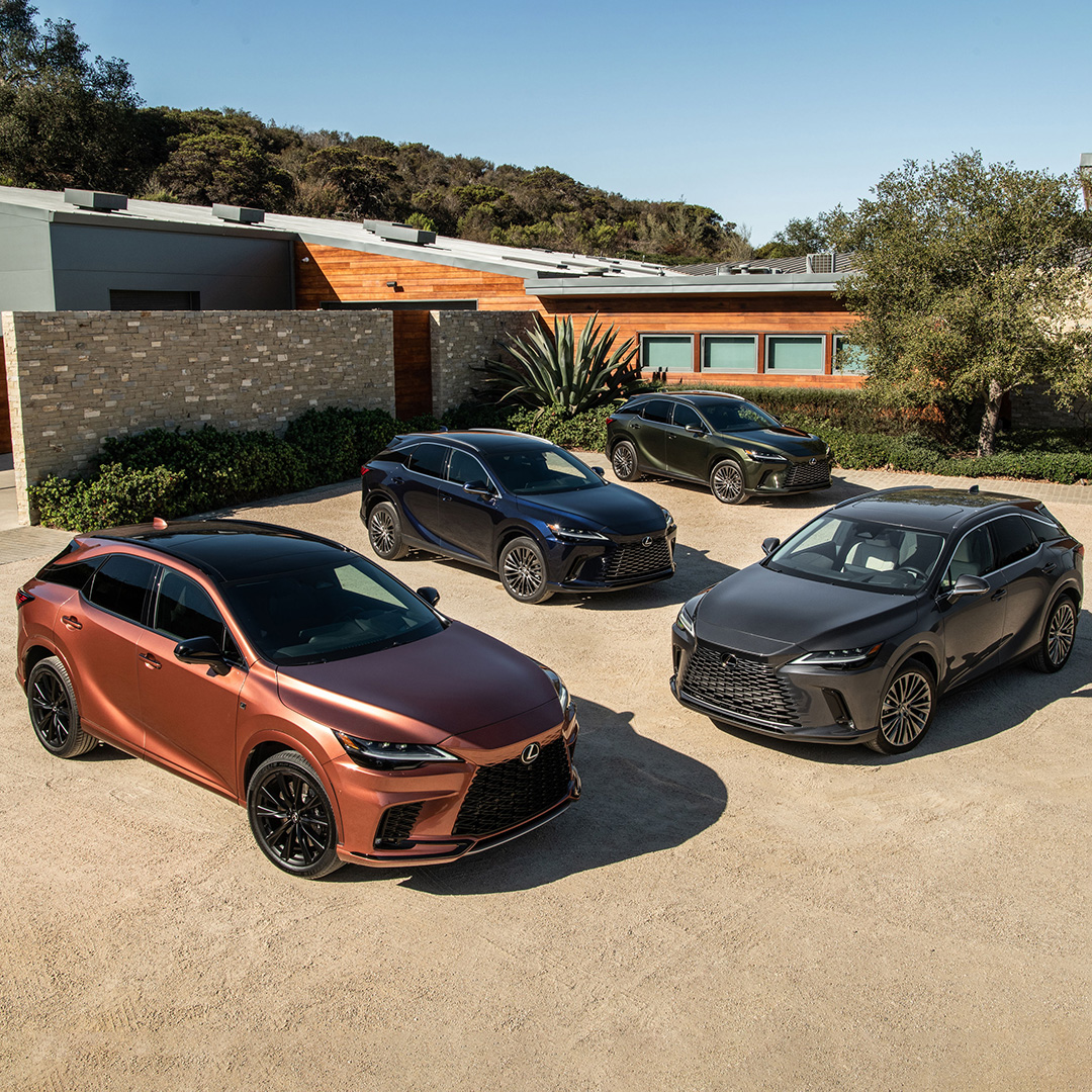 Four differently coloured Lexus RX models parked in the driveway of a contemporary luxury home.