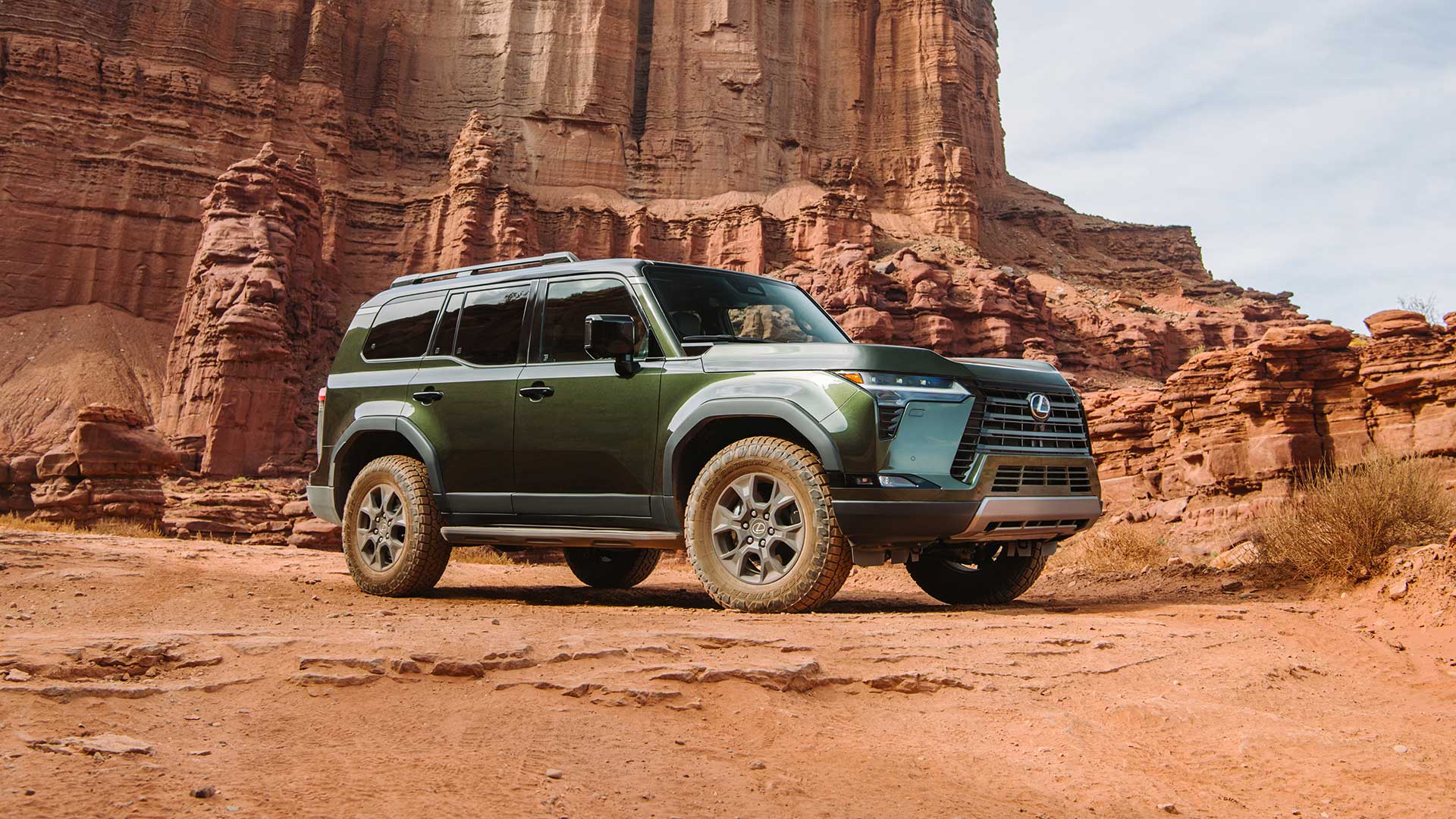 A green Lexus GX parked on a cracked red earth ground