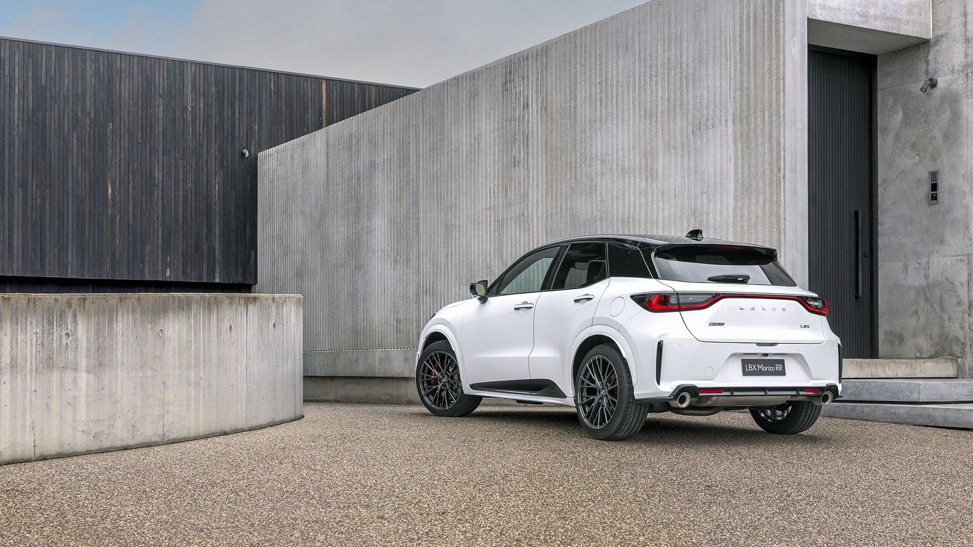 A white Lexus LBX Morizo RR parked in front of a cement building